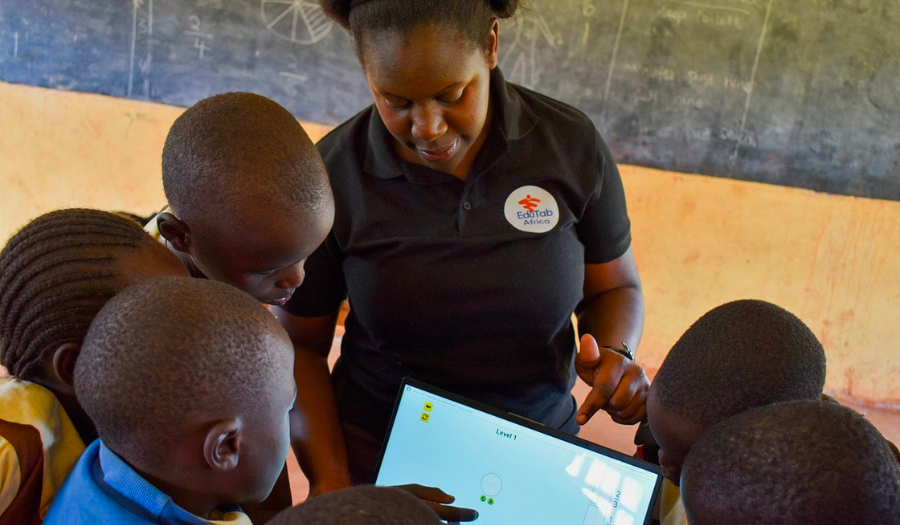 A teacher shows a tablet with the Fractions: Intro simulation to five elementary students.