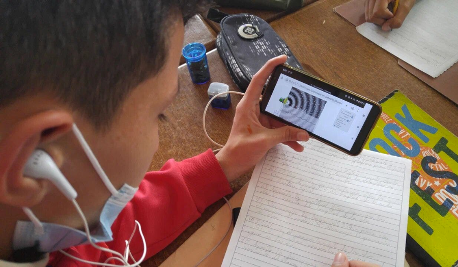 A student uses the Waves: Intro simulation as he takes notes.